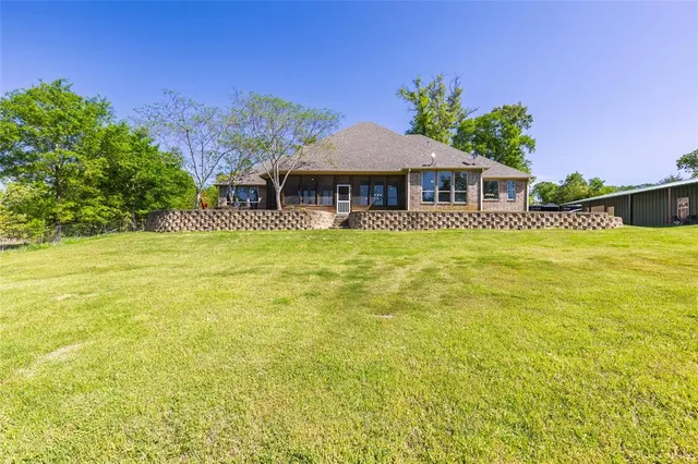 a blue swimming pool is in front of a big yard with potted plants