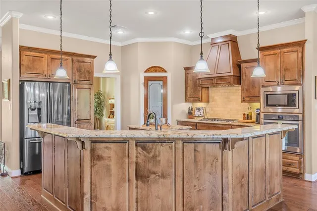 a kitchen with stainless steel appliances granite countertop a sink a oven and a refrigerator with wooden floor