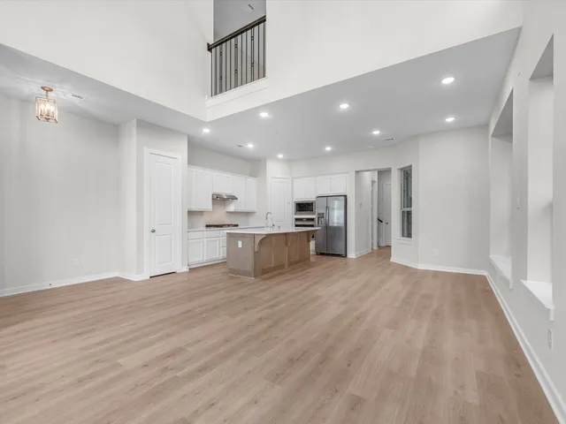 a view of kitchen with kitchen island wooden floor center island and stainless steel appliances