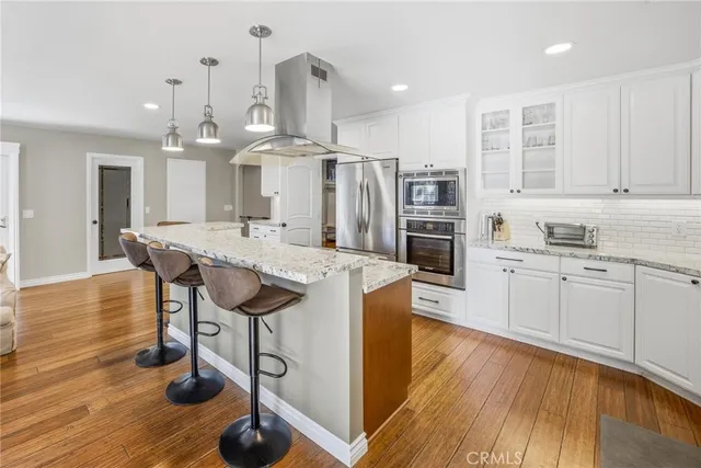 a kitchen with stainless steel appliances wooden floor sink and wooden cabinets