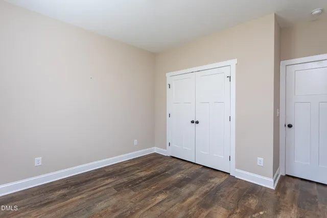 a view of an empty room with wooden floor and closet