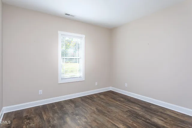 an empty room with wooden floor and window