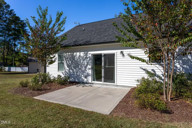 a view of a white house with a small yard and potted plants
