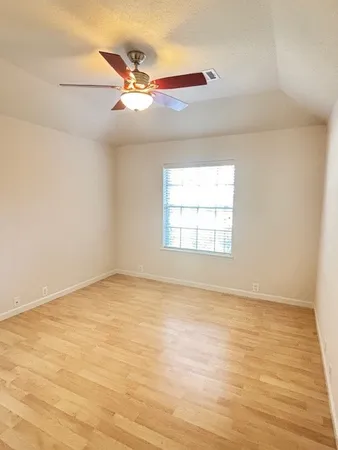 an empty room with wooden floor fan and windows