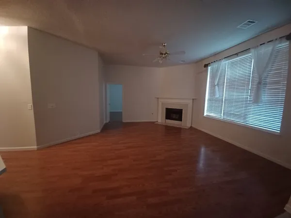 a view of empty room with fireplace and wooden floor