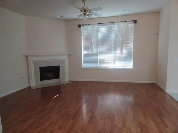 an empty room with wooden floor fireplace and windows