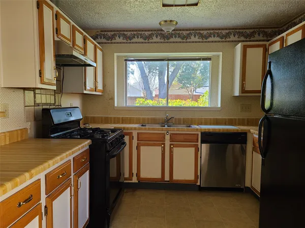 a kitchen with stainless steel appliances a stove window and cabinets