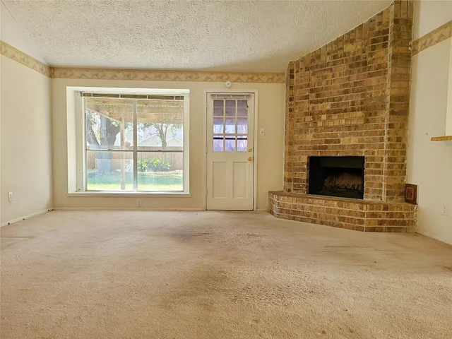 an empty room with windows and fireplace