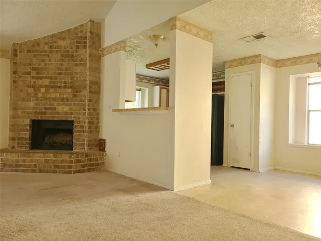 a view of an empty room with a fireplace and a window