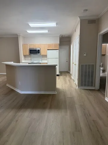 a view of a kitchen with kitchen island wooden floors and stainless steel appliances