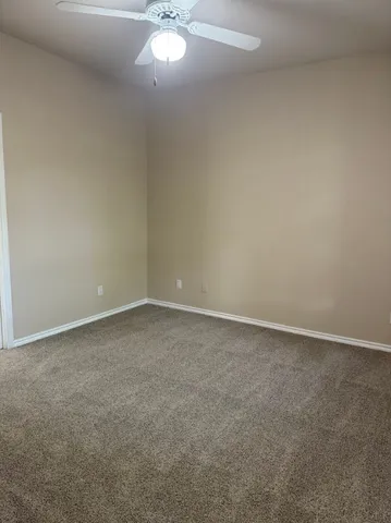 a view of an empty room and a chandelier fan