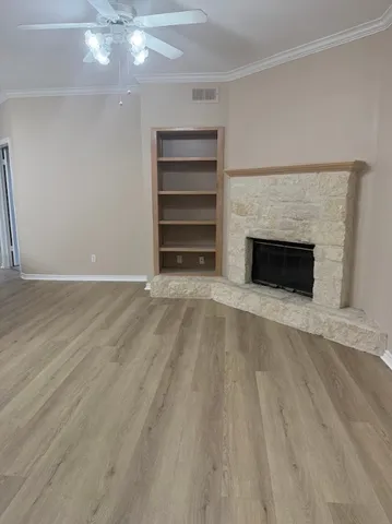 a view of an empty room with wooden floor fireplace and a window