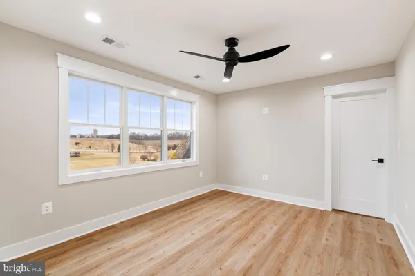 a view of an empty room with a window and wooden floor