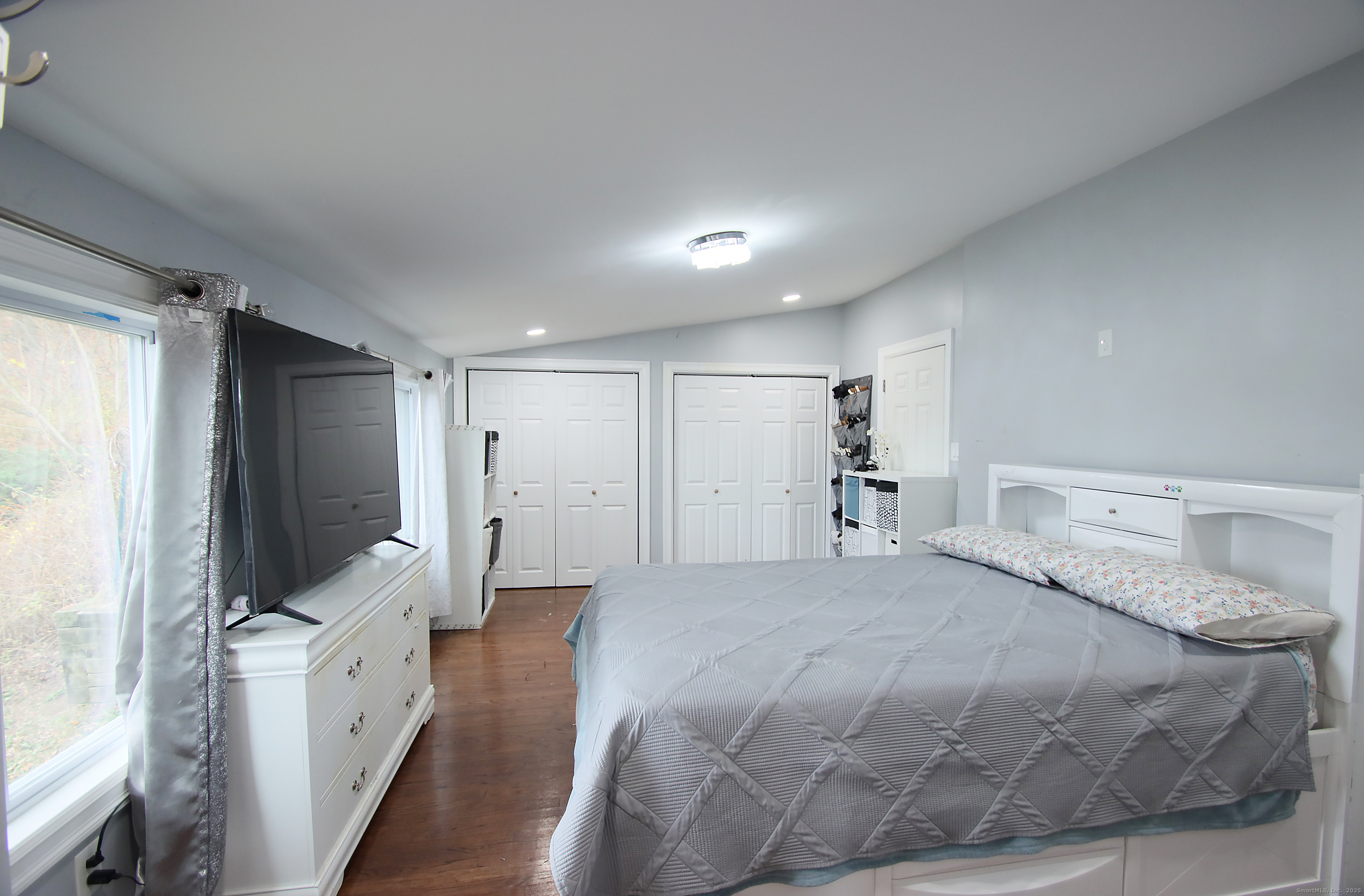 32 Spring Street Ansonia, CT 06401 - Photo 13 of 34 a spacious bedroom with a large bed and a flat tv screen on dresser