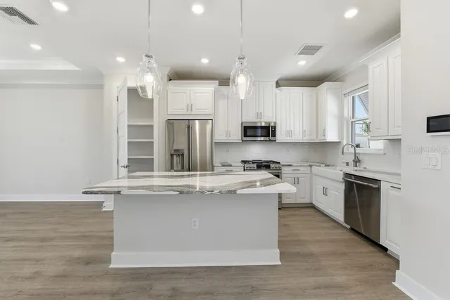 a large kitchen with stainless steel appliances granite countertop a stove a sink and a refrigerator