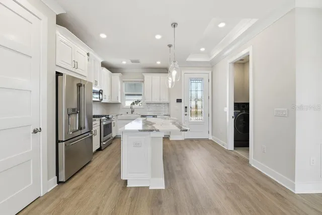 a kitchen with kitchen island wooden floors appliances and cabinets