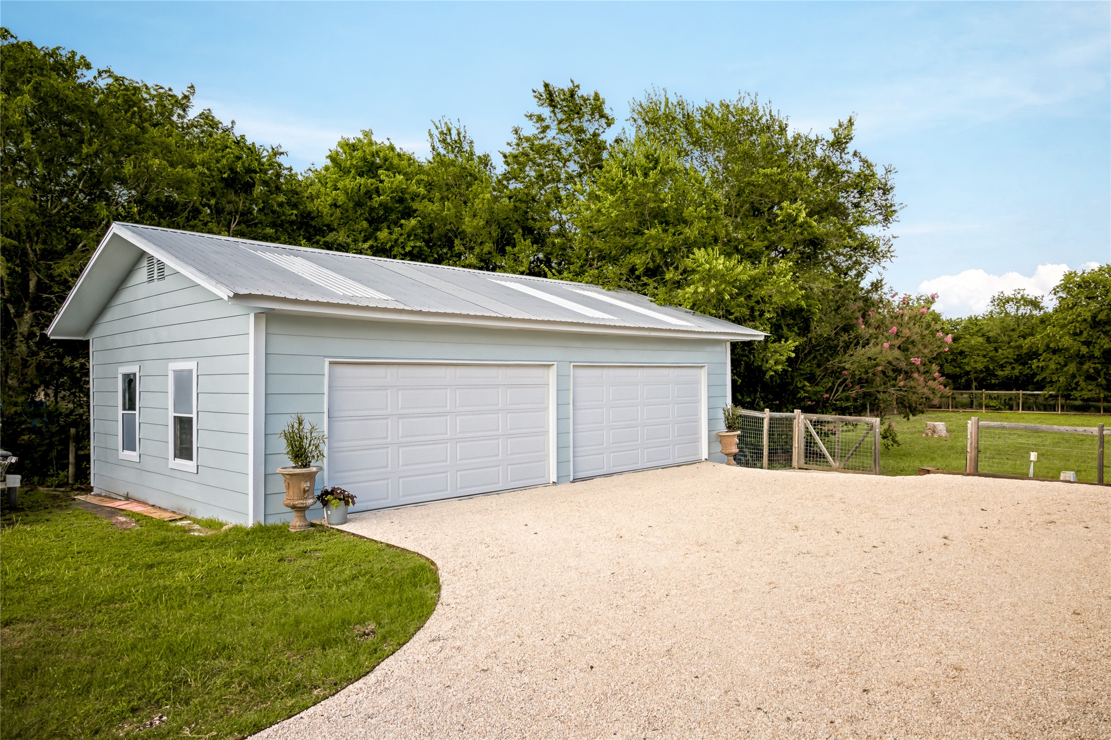 372 Old Lockhart Road Lockhart, TX 78644 - Photo 33 of 40 Two-car garage with a gravel driveway and fencing, offering ample parking and outdoor space.