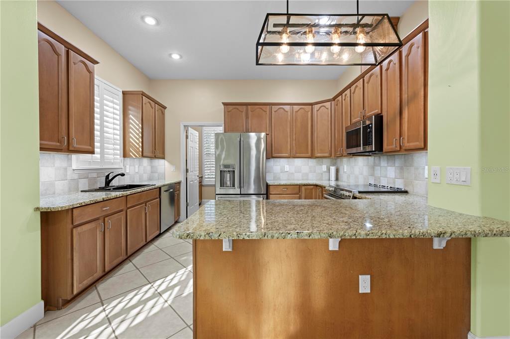 5446 Bluepoint Drive Port Richey, FL 34668 - Photo 37 of 68 a kitchen with stainless steel appliances granite countertop a sink a stove cabinets counter space and a window