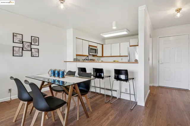 a kitchen with stainless steel appliances granite countertop a stove a refrigerator a kitchen island a dining table and chairs with wooden floor