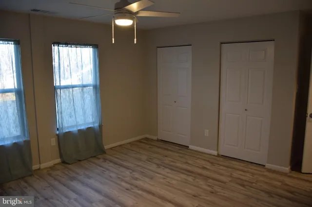 an empty room with wooden floor and windows