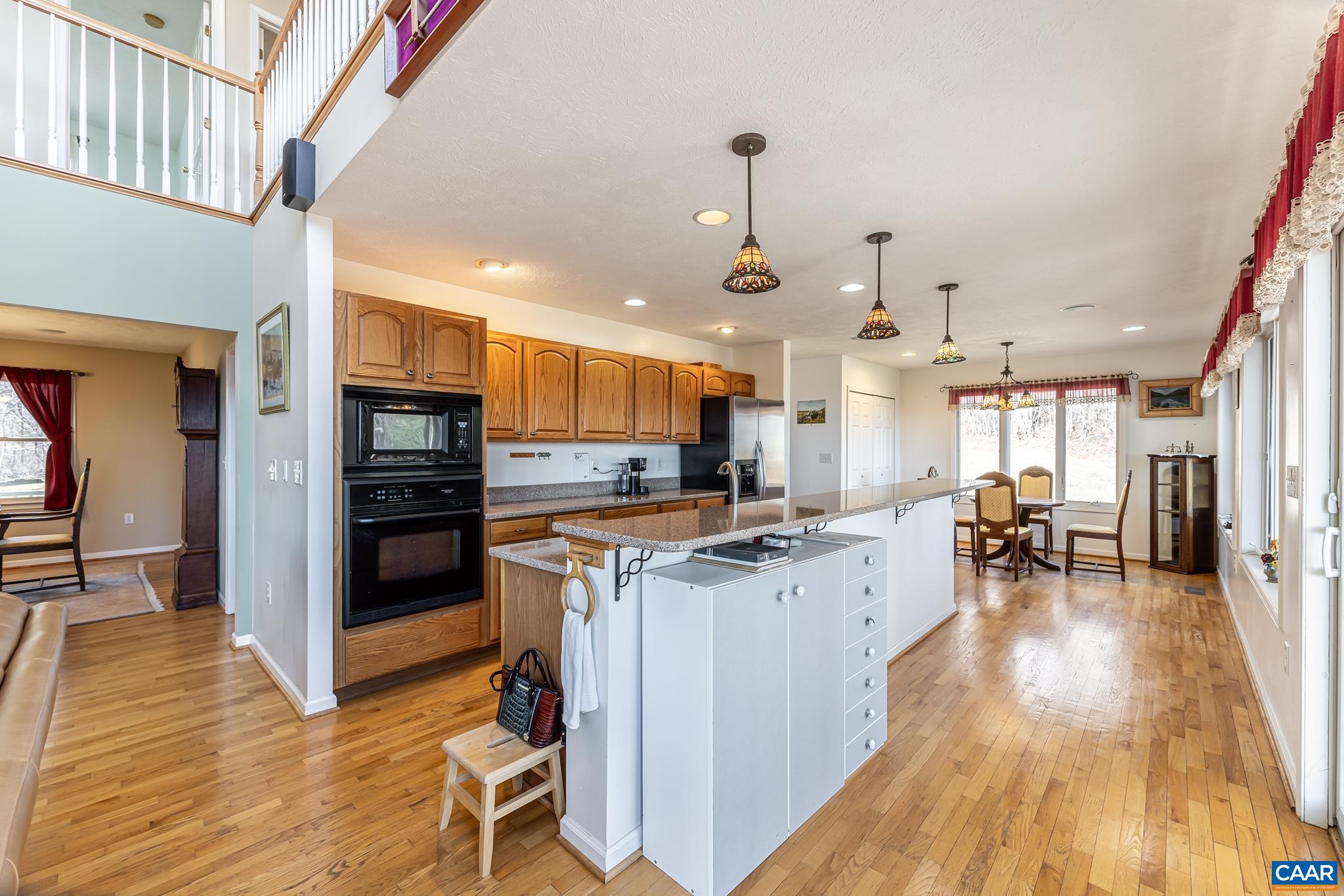 654 Saddleback Road Stanardsville, VA 22973 - Photo 10 of 75 a kitchen with stainless steel appliances kitchen island granite countertop a stove top oven a sink a dining table and chairs with wooden floor