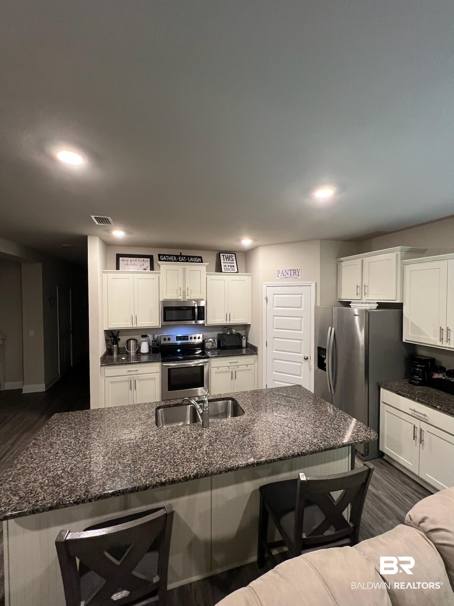 3904 Conrad Court Gulf Shores, AL 36542 - Photo 7 of 24 Kitchen featuring a kitchen bar, dark hardwood / wood-style floors, white cabinets, and stainless steel appliances