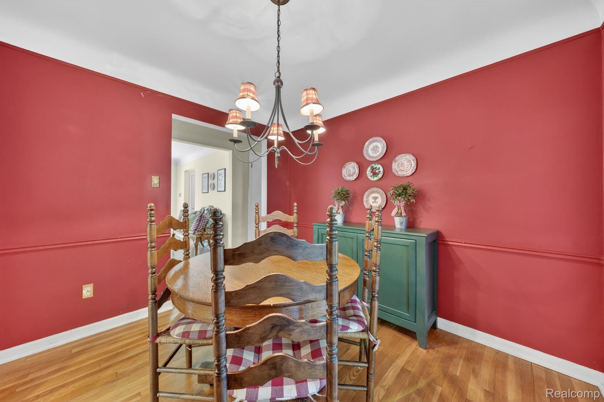 17386 Beverly Road Franklin, MI 48025 - Photo 9 of 28 Dining space featuring red walls with chair rail molding, wood-finish flooring, a ceiling-mounted chandelier, and white crown molding