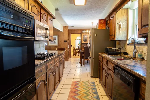 a kitchen with stainless steel appliances granite countertop a stove a sink and a refrigerator