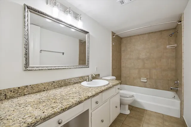 a bathroom with a granite countertop sink a toilet and a bathtub