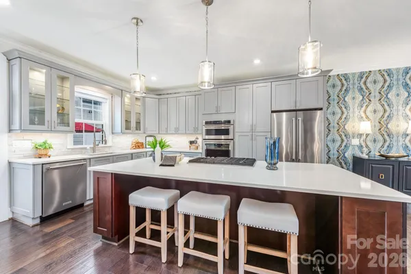 a kitchen with kitchen island a dining table chairs sink and white appliances