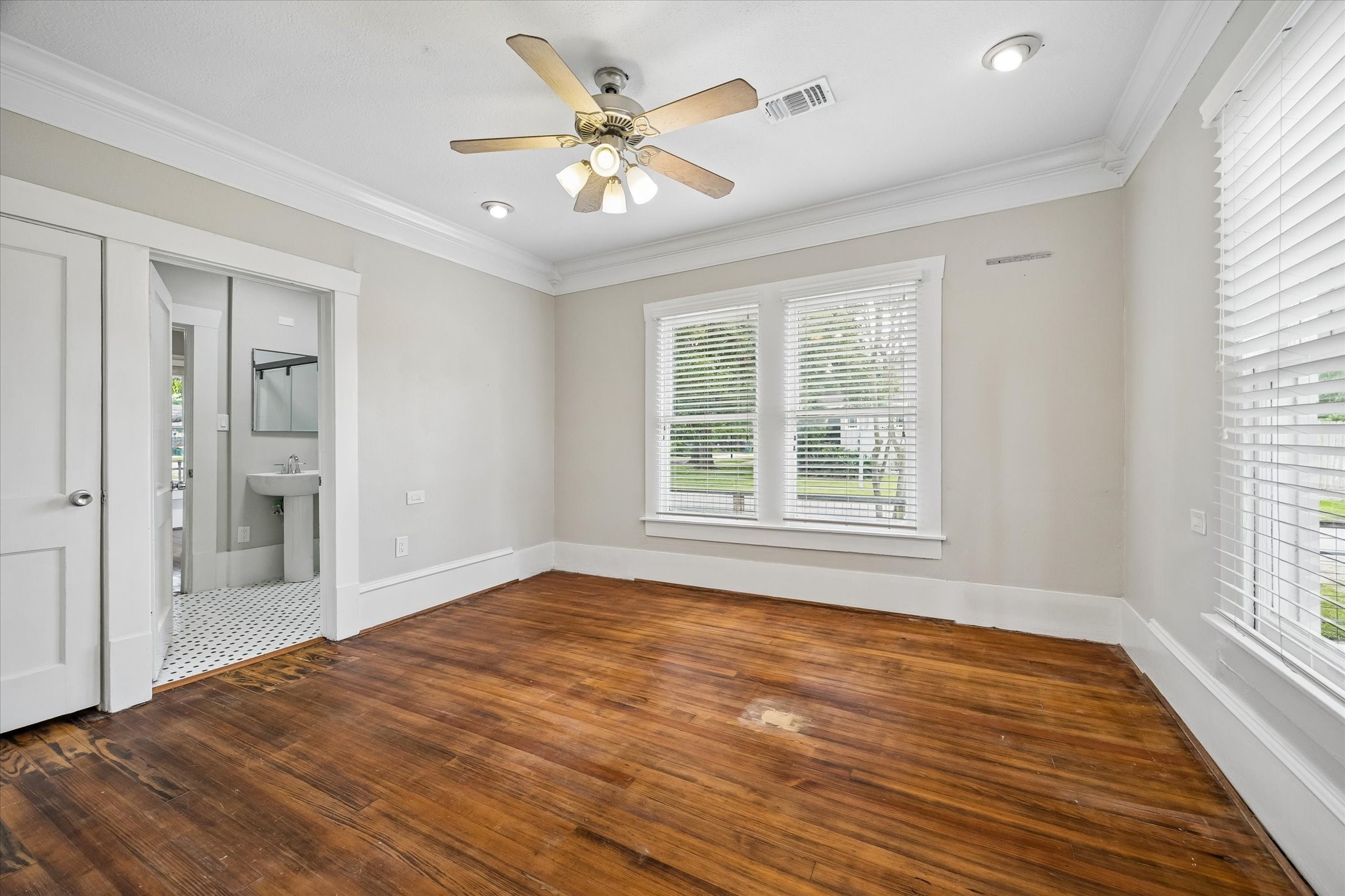 1201 Tulane Street Houston, TX 77008 - Photo 18 of 31 Another roomy bedroom keeps the same warm Heights character with hardwood floors, oversized windows, crown molding, fresh neutral paint, and updated lighting. It feels bright, comfortable, and spacious enough to be a primary suite, home office, or creative studio.