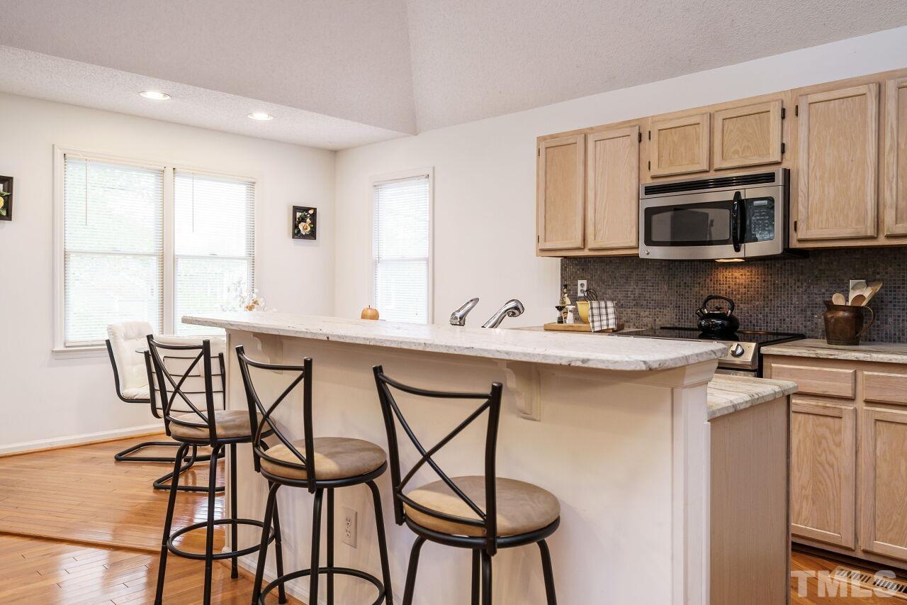 5305 Calverton Drive Raleigh, NC 27613 - Photo 11 of 34 a kitchen with stainless steel appliances kitchen island granite countertop a table chairs sink and cabinets