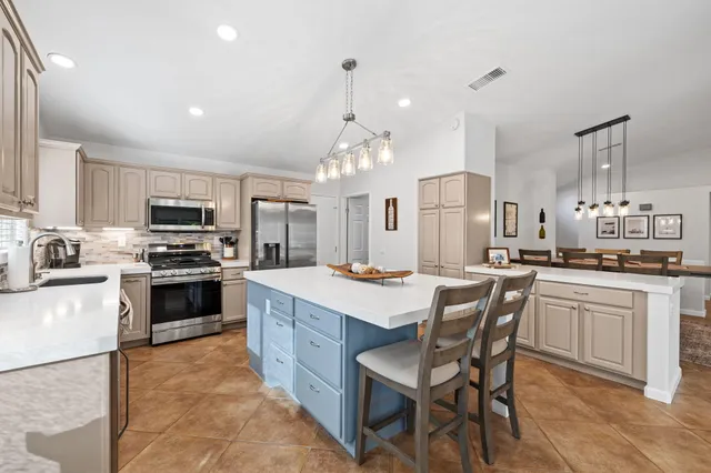 a kitchen with stainless steel appliances granite countertop a stove top oven a sink dishwasher a dining table and chairs with wooden floor