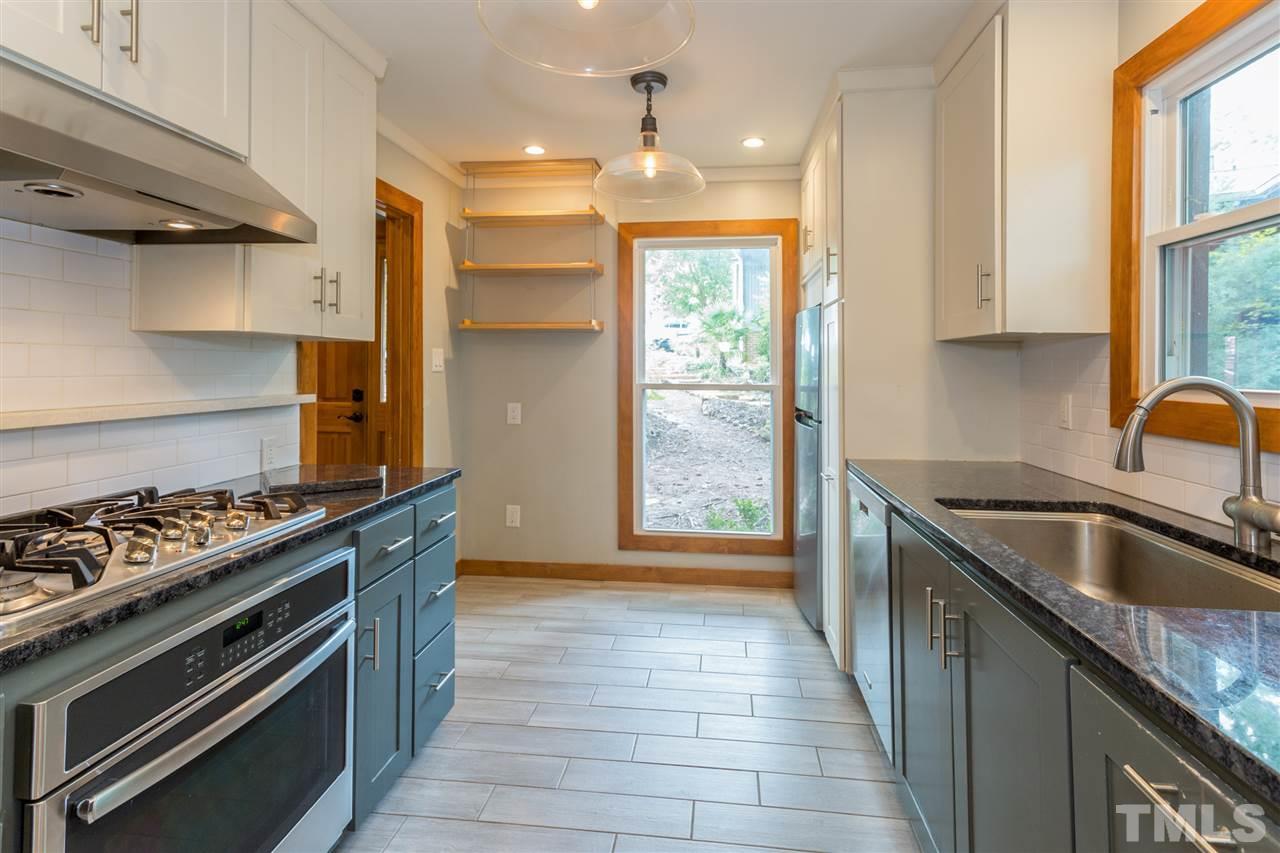 2733 Rue Sans Famille Raleigh, NC 27607 - Photo 7 of 25 a kitchen with kitchen island granite countertop a sink stove and refrigerator