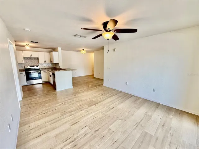 a view of a kitchen with wooden floor a sink a refrigerator and window