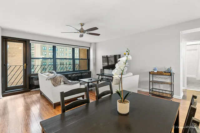 a living room with furniture a floor to ceiling window and wooden floor
