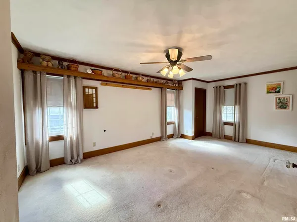 an empty room with ceiling fan and windows