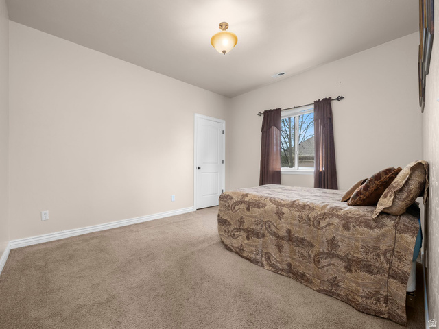 255 East 1200 North Mapleton, UT 84664 - Photo 21 of 37 Carpeted room featuring a white paneled door with black hardware, a ceiling-mounted light fixture, and a window with neutral-toned drapes
