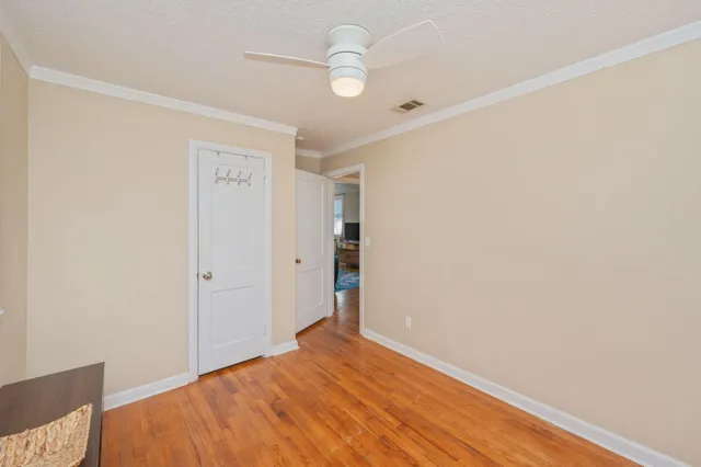 a view of empty room with wooden floor and fan