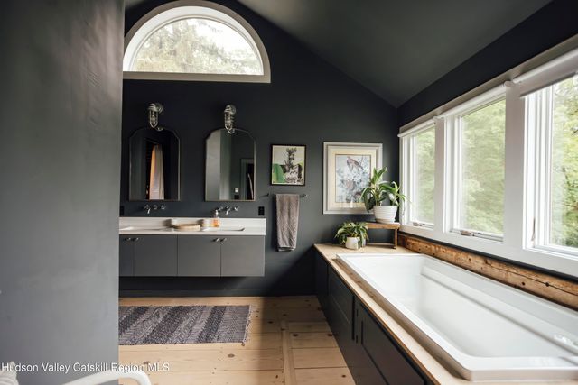 a bedroom with a bed a large window with wooden floor