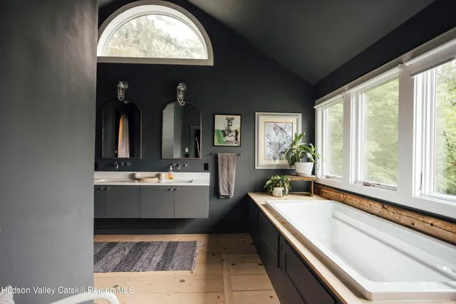 a bedroom with a bed a large window with wooden floor