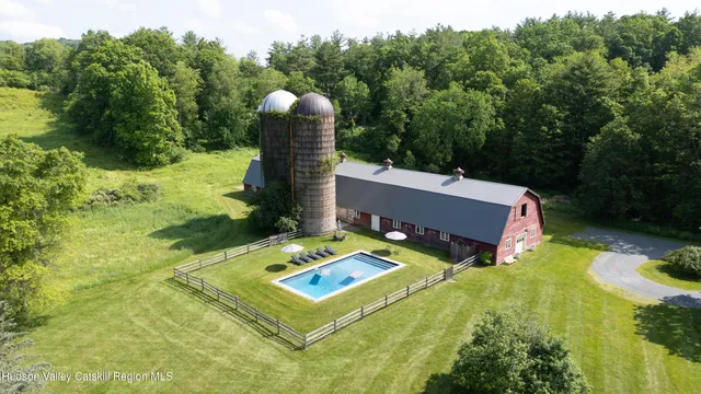 a aerial view of a house with pool water and trees in the background