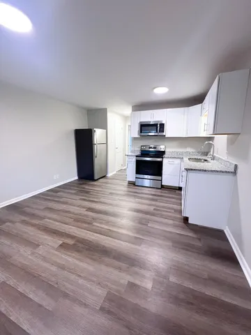a kitchen with stainless steel appliances wooden floor and a refrigerator