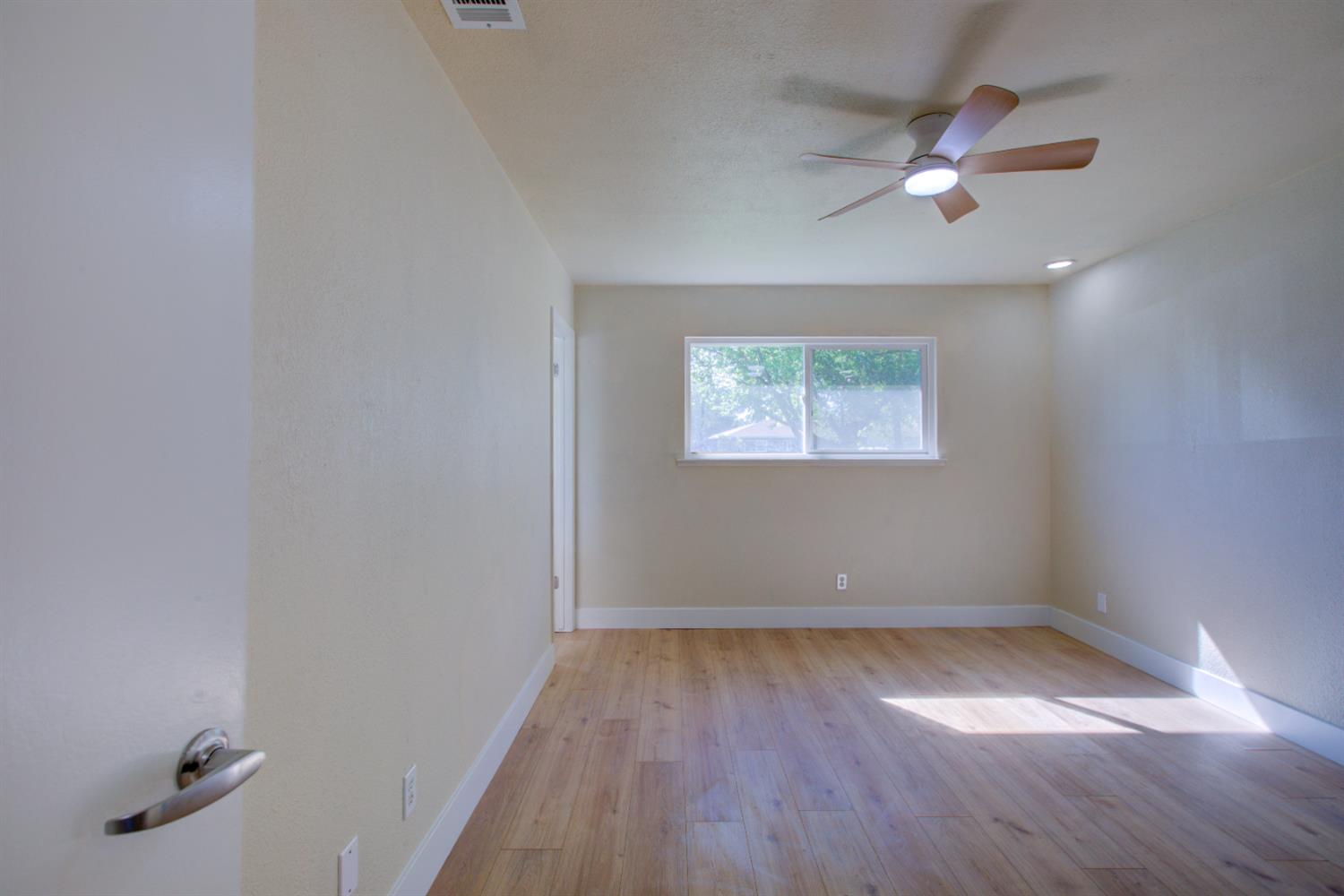 1673 Sacramento Drive Merced, CA 95348 - Photo 21 of 35 an empty room with wooden floor chandelier fan and windows