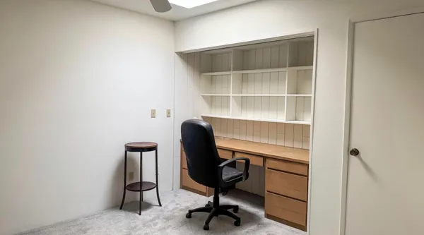 a view of a workspace with furniture and a window