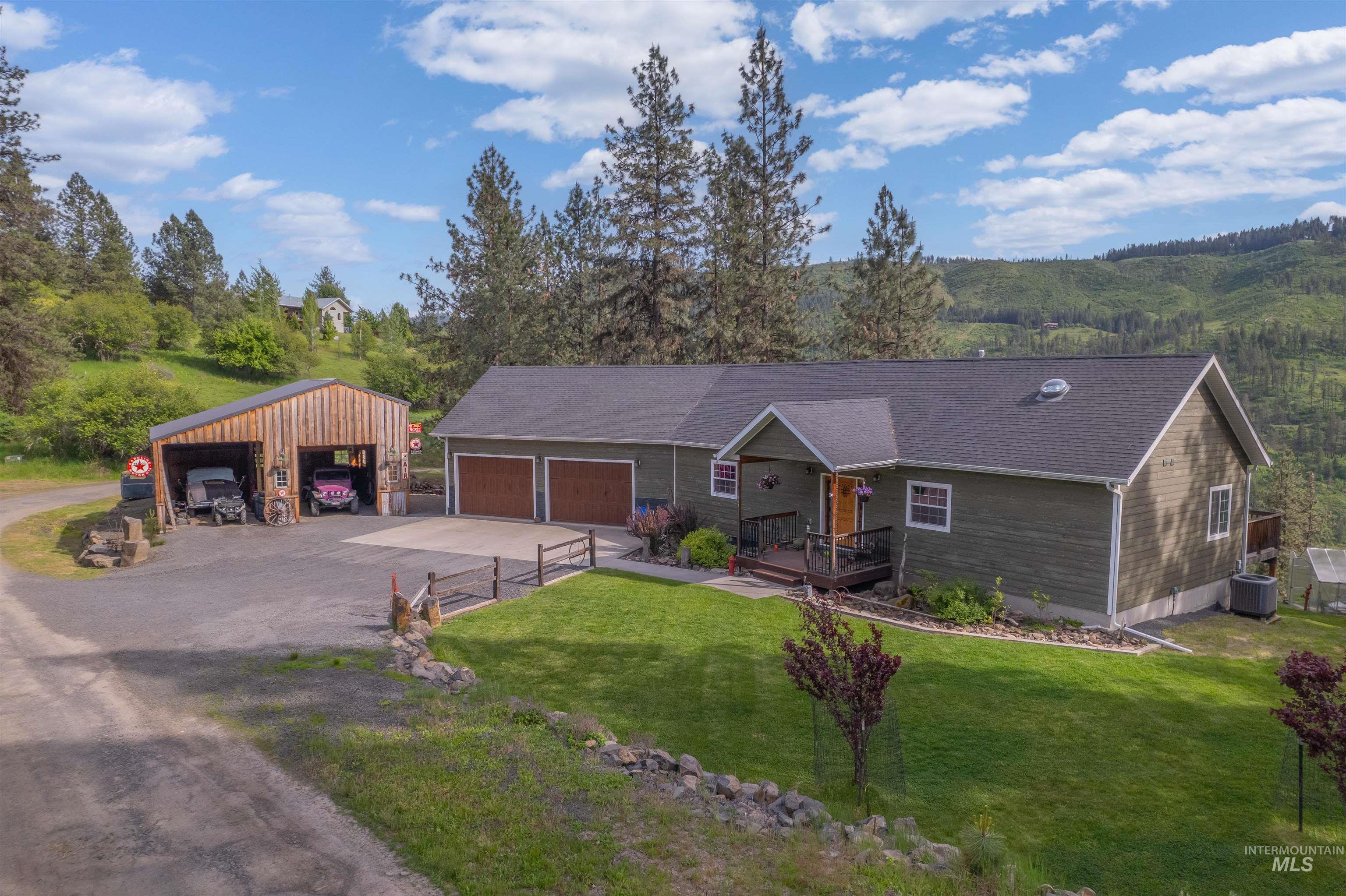 Single story home featuring driveway, a front yard, an outdoor structure, covered porch, and a garage