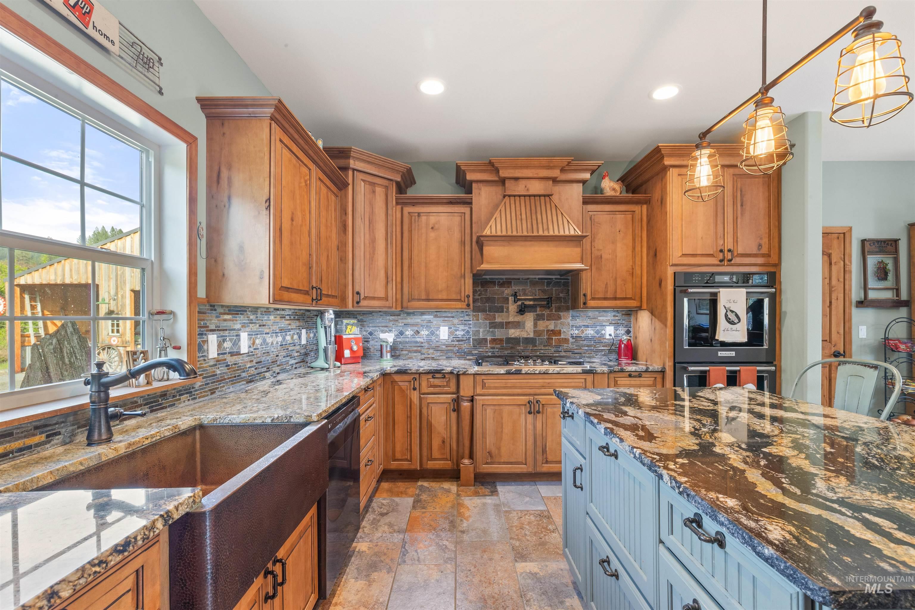 643 Adams Road Orofino, ID 83544 - Photo 14 of 50 Dual tone kitchen with dual tone cabinets, dark stone countertops, double oven, stone tile floors, and decorative backsplash