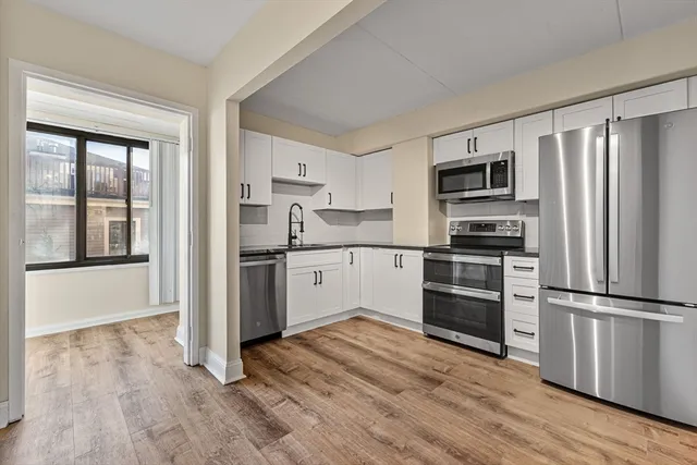 a kitchen with a refrigerator stove and wooden floor