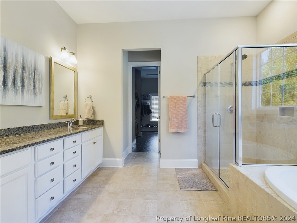 4001 Banks Stone Drive Raleigh, NC 27603 - Photo 20 of 50 a bathroom with a granite countertop sink a mirror a shower and a bathtub