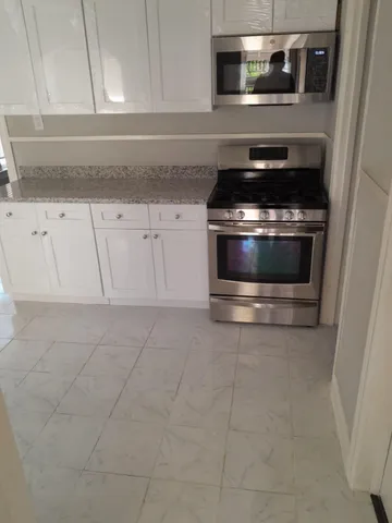 a kitchen with granite countertop white cabinets and stainless steel appliances